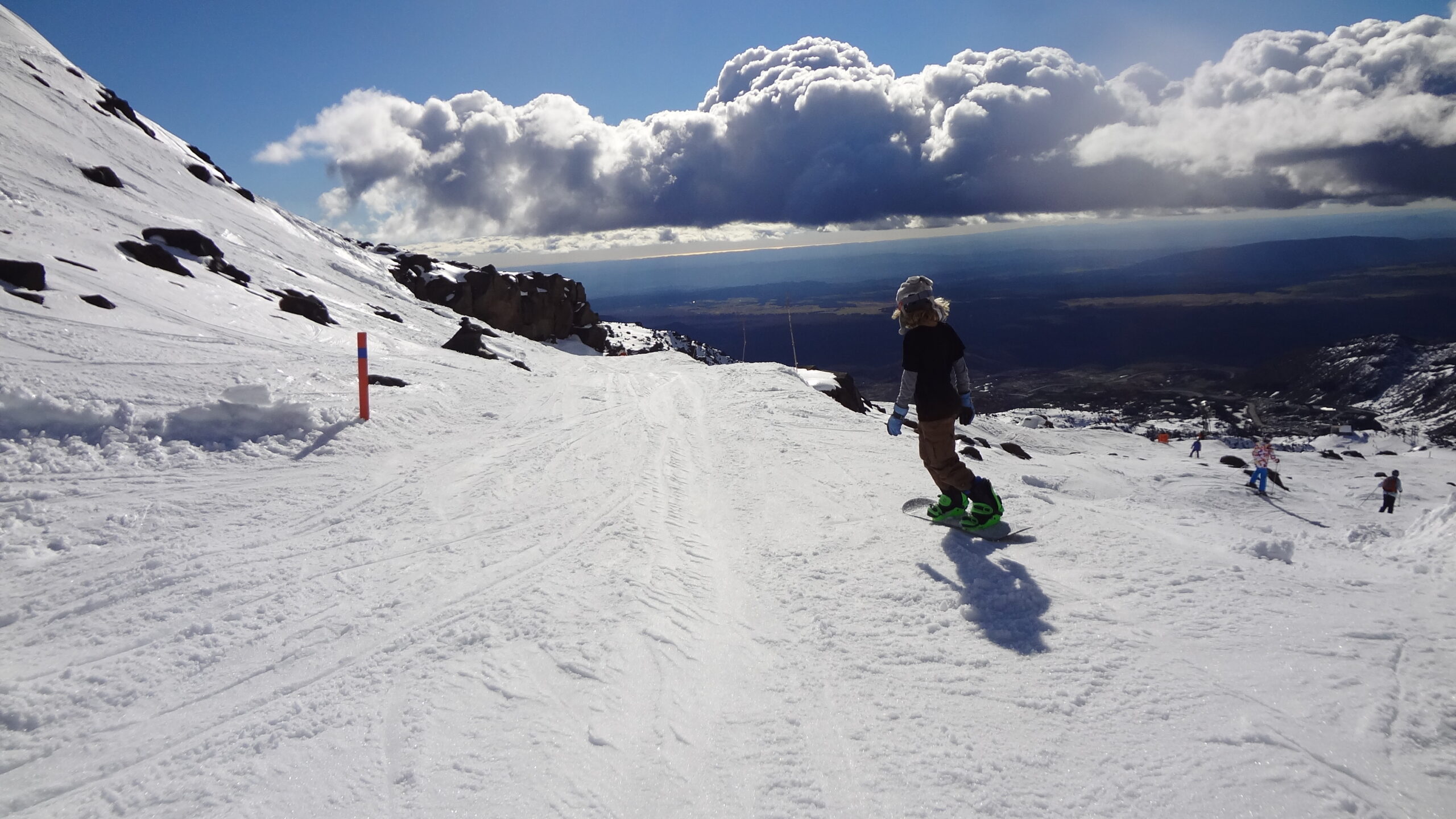 Snowboarder riding down a slope on Mt Ruapehu, framed by rolling cloud