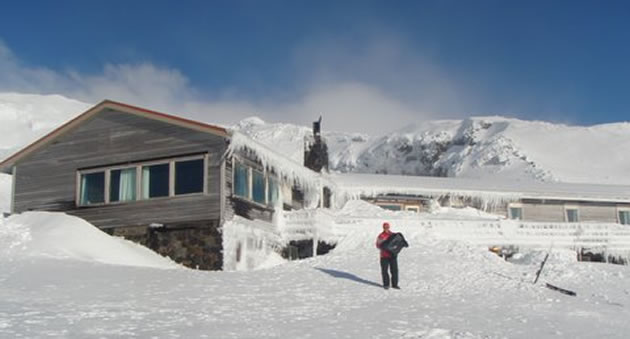 Member standing outside an ice-covered lodge after a snowstorm